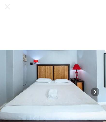 a bedroom with a large white bed with a red lamp at Hotel Le Carmen in Cebu City