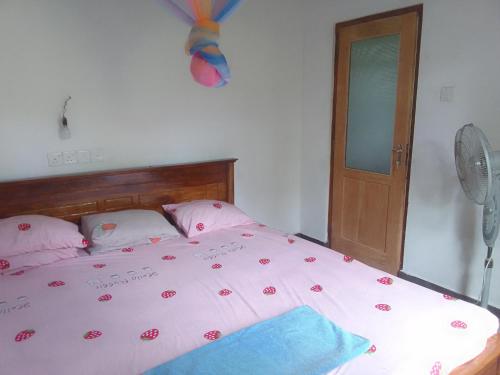 a bedroom with a bed with pink sheets and a fan at Villa tharu hikkaduwa in Hikkaduwa