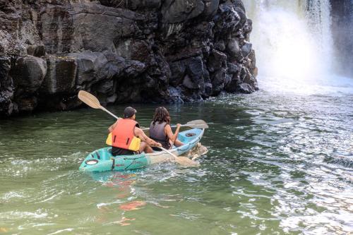 two people and a dog in a kayak in front of a waterfall at EvaZion River Side in Grande Rivière Sud Est