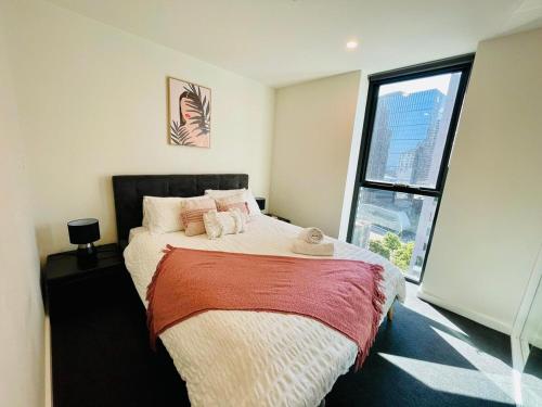 a bedroom with a large bed with a large window at Comfy Unit in front of Crown with Free Parking in Melbourne