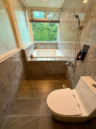 a bathroom with a toilet and a bath tub at 自在旅墅山莊 in Guoxing