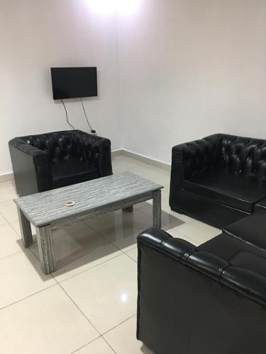a living room with two black leather couches and a table at Apple Luxury Apartments in Kigali