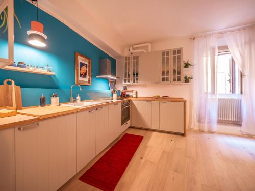 a kitchen with blue walls and white cabinets and a red rug at La Casa di Nina e la Luna in Perugia