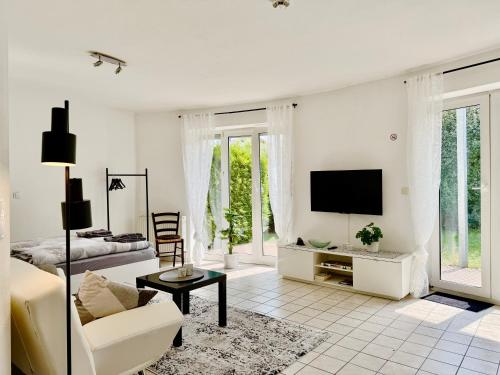 a white living room with a couch and a tv at Kleines Idyll, Ruhig & erholsam - Peter M22 - Frankenwald Apartments in Stadtsteinach