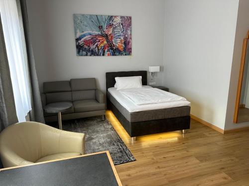a bedroom with a bed and a couch and a chair at Apartment Hotel KRAL - BUSINESS HOTEL & SERVICED APARTMENTS in Erlangen