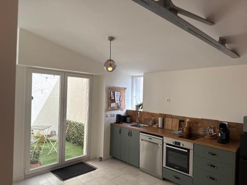 a kitchen with stainless steel appliances and a large window at Bienvenue à la maison in Saint-Florentin