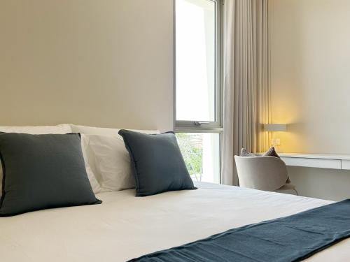 a bed with blue and white pillows and a window at Peace Nakhon Nayok in Nakhon Nayok