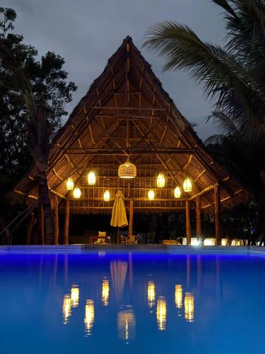a large building with a swimming pool at night at Hostel 197 in Nungwi