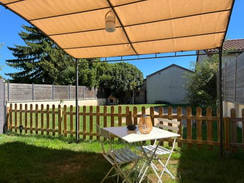 a table and chairs under an umbrella in a yard at Charmant studio à 10 min de Lyon in Miribel