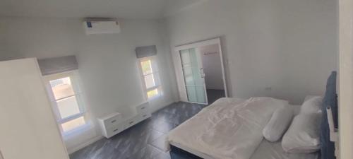 a white bedroom with a bed and two windows at Avipoolvilla in Hang Dong