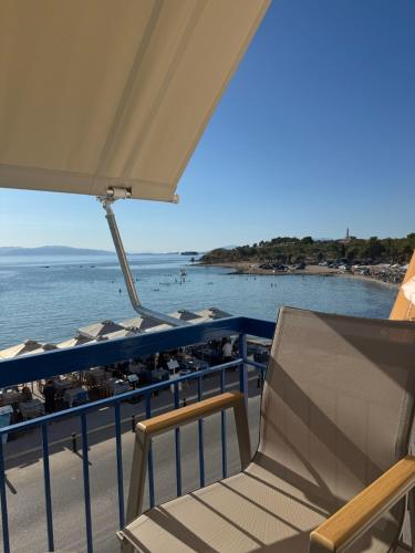 a balcony with a chair and a view of the ocean at Hotel Avra in Aegina Town