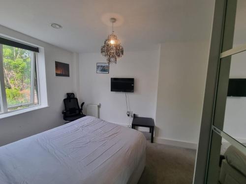 a bedroom with a white bed and a chandelier at Sweet Ivy 1 Bedroom Tottenham in London