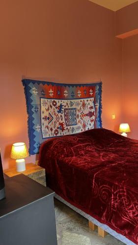 a bedroom with a large red bed with two lamps at ANDRIANA Mountain Home - ASPRIAS 