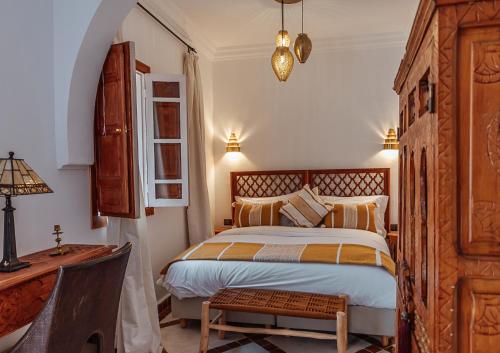 una camera da letto con un letto, un tavolo e una scrivania di Riad Le Terracotta a Marrakech