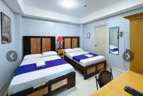 a bedroom with two beds and a desk with a computer at Hotel Le Carmen in Cebu City