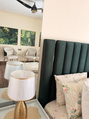 a bedroom with a green headboard and a table with a lamp at Mountain view cottage in Murree