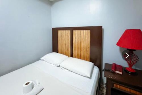 a bedroom with a bed with a red lamp on a table at Hotel Le Carmen in Cebu City