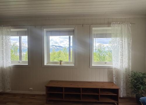 a room with three windows and a wooden table at Casa Sápmi in Tromsø