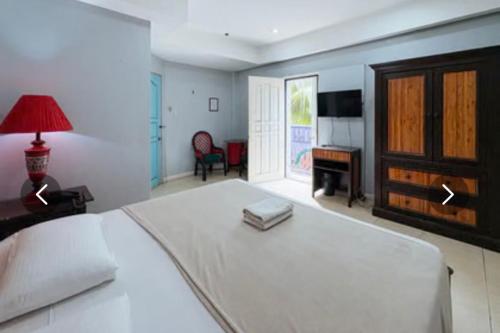 a bedroom with a large white bed and a desk at Hotel Le Carmen in Cebu City