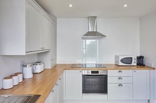 a white kitchen with white cabinets and a microwave at 96 Roseberry Cottage in the market town of Guisborough in Guisborough