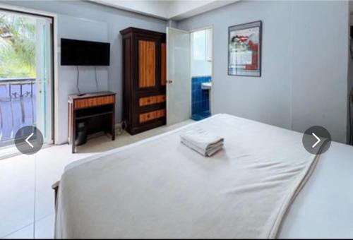 a white bedroom with a bed and a television at Hotel Le Carmen in Cebu City