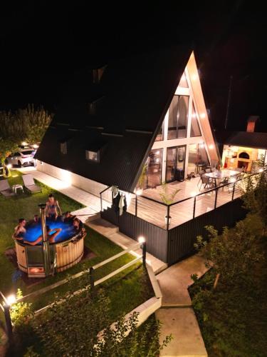 a house with a hot tub in the yard at night at Cabana Serenity - A-frame in Pucheni