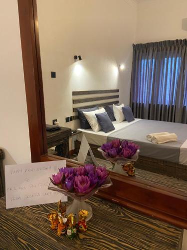 a bedroom with a bed and two bowls of flowers on a table at Sesatha lake Kandy in Kandy