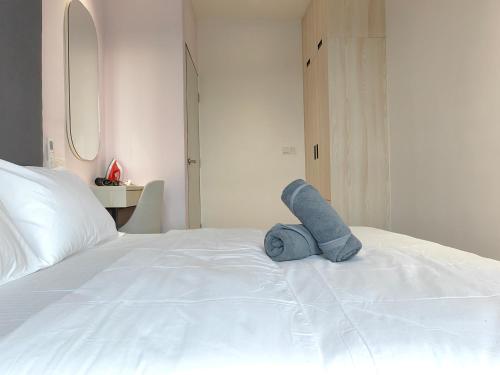 a blue teddy bear sitting on a white bed at Vetro11 Beside QEH1 by JUNE Homestay in Kota Kinabalu
