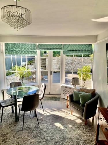 a living room with a table and chairs and windows at The Annexe Westbury House in Great Dunmow