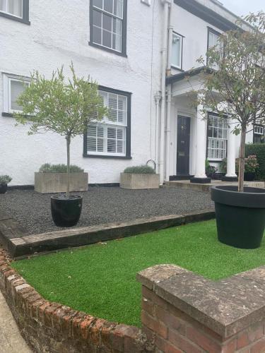 two trees in pots in front of a house at The Annexe Westbury House in Great Dunmow