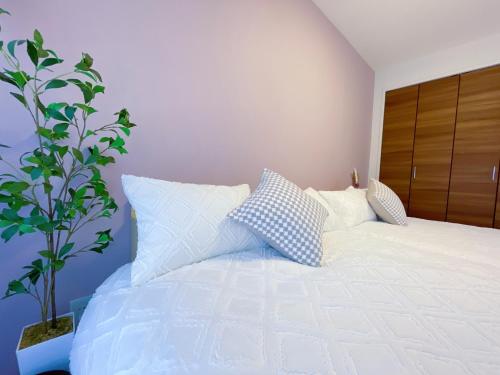 a bedroom with a white bed and a plant at 新宿御苑 徒歩8分 新宿三丁目駅徒歩8分 WiFi無料 in Tokyo