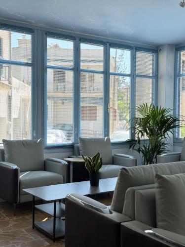 a waiting room with chairs and a table and windows at Hotel Avra in Aegina Town