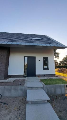 a small white house with a black door at Vakantiewoning OpdeBaan in Kaatsheuvel