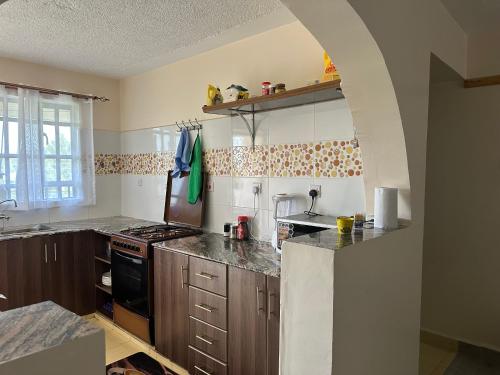 una cocina con armarios de madera y un arco en Jrungaru BnB, en Nanyuki