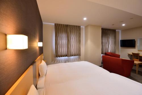 a bedroom with a white bed and a red chair at Hotel Urbic Kagoshima in Kagoshima