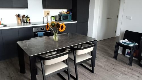 Una cocina con una mesa con un jarrón de flores encima. en Room in a Luxury apartment in Central London -Private toilet, en Londres