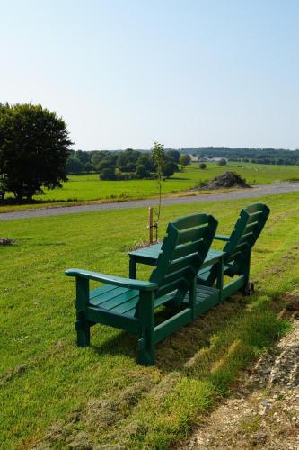 two green chairs and a table in a field at Gîte Meunier, tu dors in Vaux-sur-Sûre
