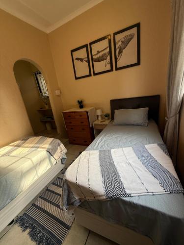 a bedroom with two beds and a dresser at Whale's Cove in Amanzimtoti
