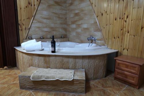 a bathroom with a tub with a bottle of wine at אחוזת רותם in Dovev