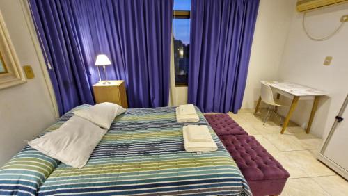 a bedroom with purple curtains and a bed and a desk at DUPLEX mc in Posadas