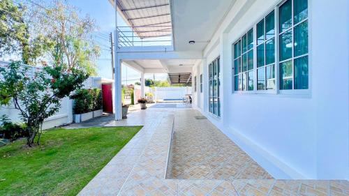 an exterior view of a white building with a walkway at บ้านย่าพลูวิลล่าพลาบ้านฉางระยอง in Ban Phala