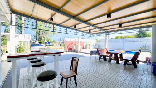 a patio with a table and chairs and a pool at บ้านย่าพลูวิลล่าพลาบ้านฉางระยอง in Ban Phala