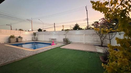 a backyard with a swimming pool and a green lawn at บ้านย่าพลูวิลล่าพลาบ้านฉางระยอง in Ban Phala