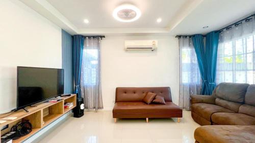 a living room with a couch and a flat screen tv at บ้านย่าพลูวิลล่าพลาบ้านฉางระยอง in Ban Phala