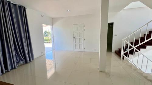 a hallway with white walls and a staircase in a house at บ้านย่าพลูวิลล่าพลาบ้านฉางระยอง in Ban Phala