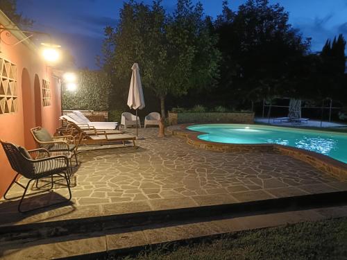 Un patio con sillas y sombrilla y una piscina. en Coaching House, en Arezzo
