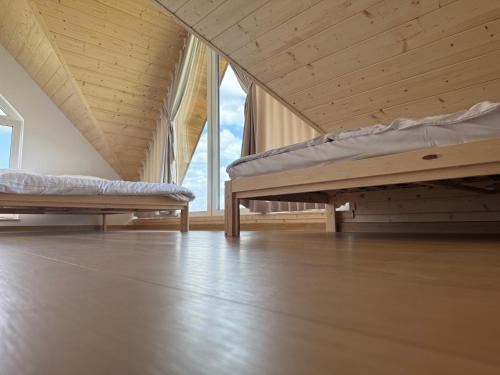 two beds in a room with wooden floors and windows at Domki Przykona in Zimotki