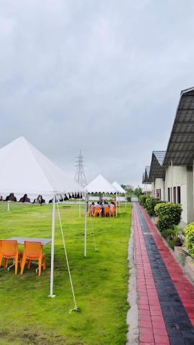 a group of tables and chairs with umbrellas in a field at Unity Sunrise Resort Best Hotel Near Statue of Unity in Kevadia