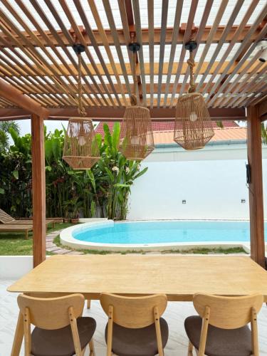 eine Terrasse mit Tisch und Stühlen und ein Swimmingpool in der Unterkunft 2BR Pool Villa&Garden - Bali style by La Perla Phuket Rawai in Ban Saiyuan (1)