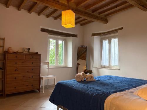 a bedroom with a blue bed with a dresser and windows at Foxes house in Monte Fabbri